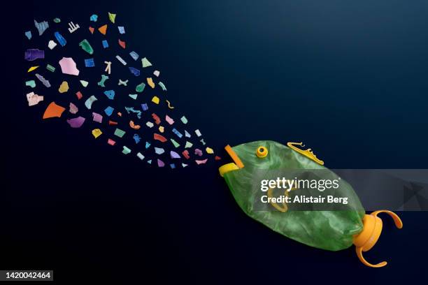 micro plastic pieces floating in the sea, being eaten by a plastic fish - plastic animals stock pictures, royalty-free photos & images