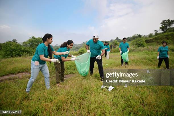group of volunteers picking up trash and plastic in the nature - limpeza ambiental imagens e fotografias de stock