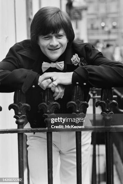 Northern Irish snooker player Alex Higgins , leaning on the railing, wearing a bow tie and a rose buttonhole on his jacket, in London, England, 13th...