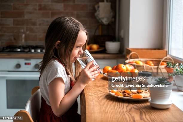 little pretty girl drinking water during her breakfast at home. happy little girl with fruits at home. - happy face glasses stockfoto's en -beelden