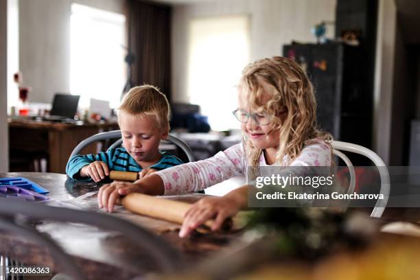 a boy and a girl with blonde curly hair make christmas cookies. - flour christmas stock-fotos und bilder