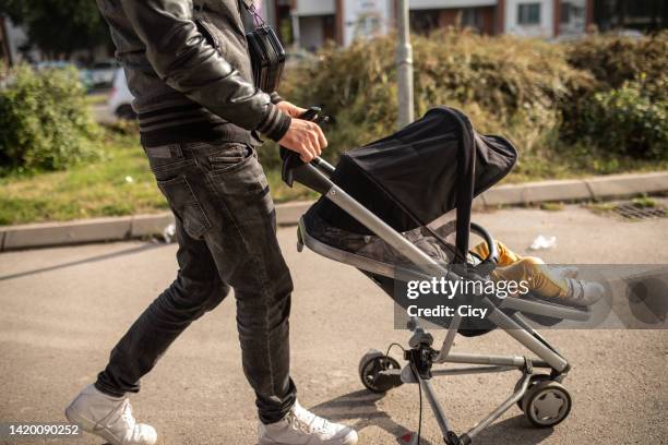 unrecognizable man pushing a baby stroller - man pushing stock pictures, royalty-free photos & images