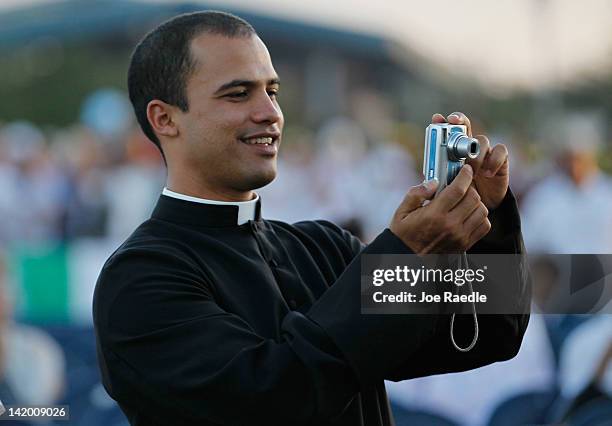 Priest takes a photograph as he waits for the arrival Pope Benedict XVI for his mass at Havana's Revolution Square on the last day of his three day...