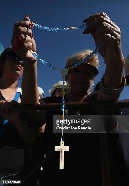 Women holds a cross as she watches as Pope Benedict XVI conducts his mass at Havana's Revolution Square on the last day of his three day visit on...