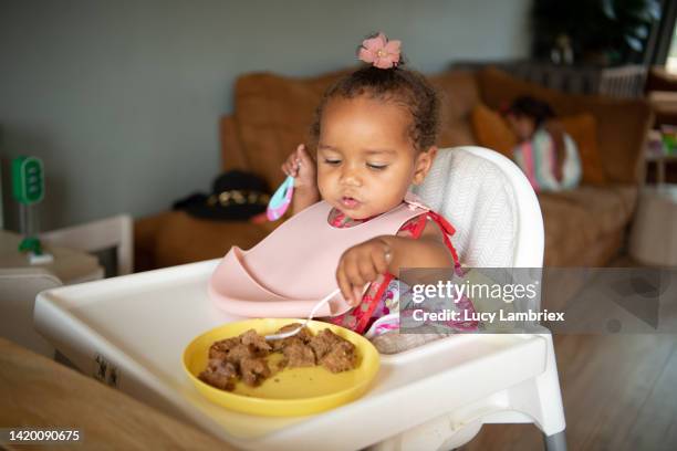 cute one-year-old eating a peanut butter sandwich - baby bib stock pictures, royalty-free photos & images