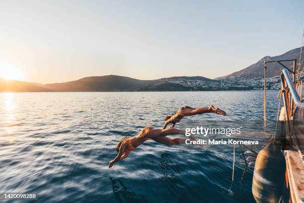 girl friend jumping in sea from sailboat. - jumping of boat foto e immagini stock