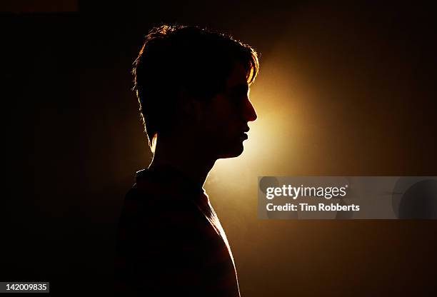 silhouette of young man. - dark background light stock-fotos und bilder