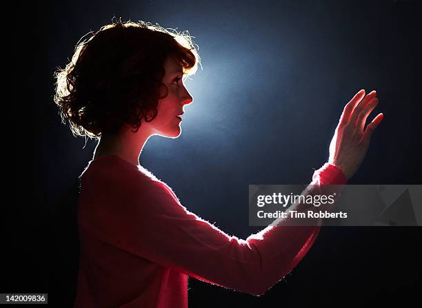 young woman reaching her arm out. - backlight stock pictures, royalty-free photos & images