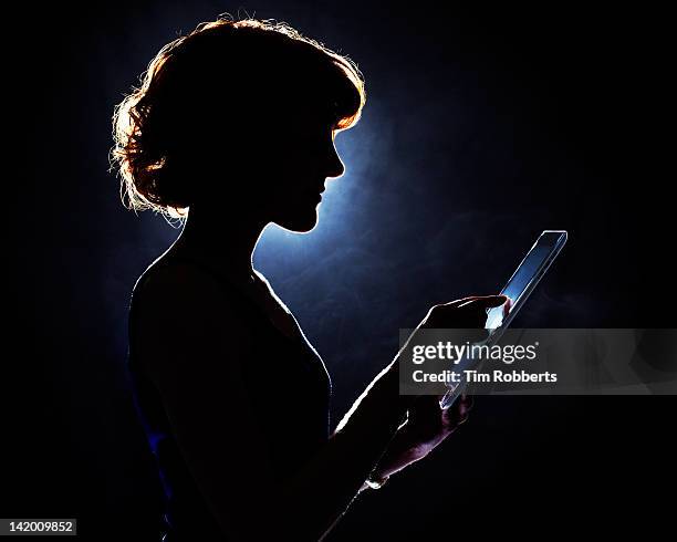 young woman using digital tablet in silhouette. - light discovery stock-fotos und bilder