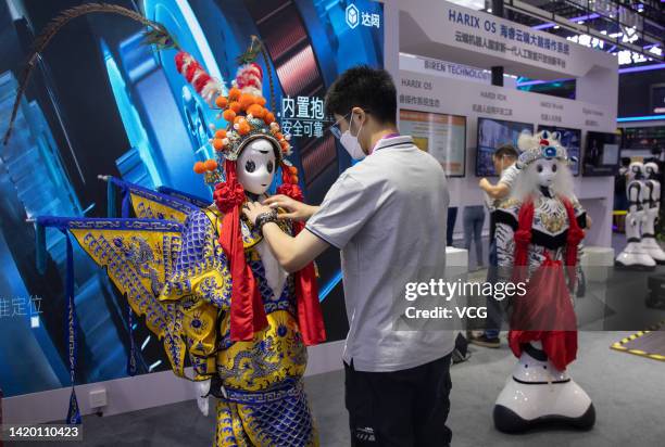Staff member prepares a robot wearing Peking Opera costume at the booth of CloudMinds Robotics during the 2022 World Artificial Intelligence...
