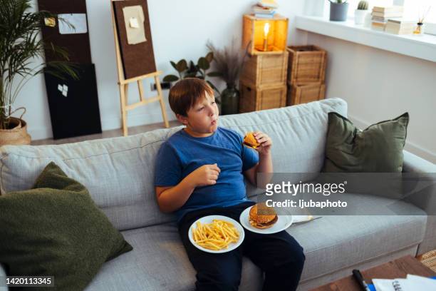 übergewichtiger teenager isst junk-food-hamburger - fat loss stock-fotos und bilder