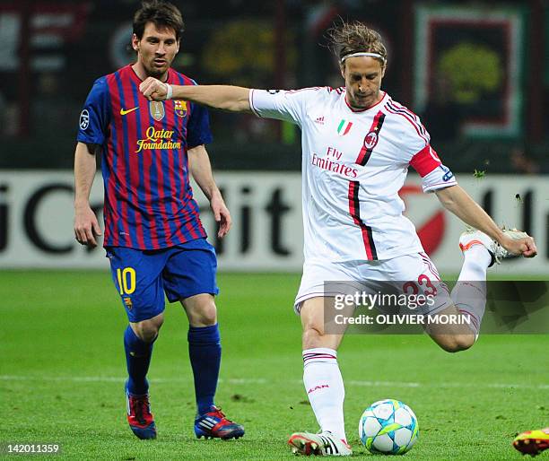 Barcelona's Argentinian forward Lionel Messi looks at AC Milan's midfielder and captain Massimo Ambrosini kicking the ball during the Champions...