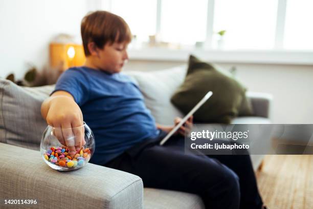 teenager-junge essen süßigkeiten während e-learning - young fat boys stock-fotos und bilder