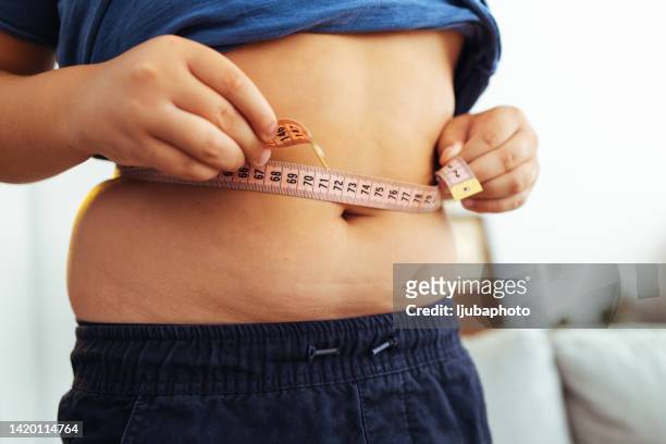fat boy seinen bauch messen - kids belly stock-fotos und bilder