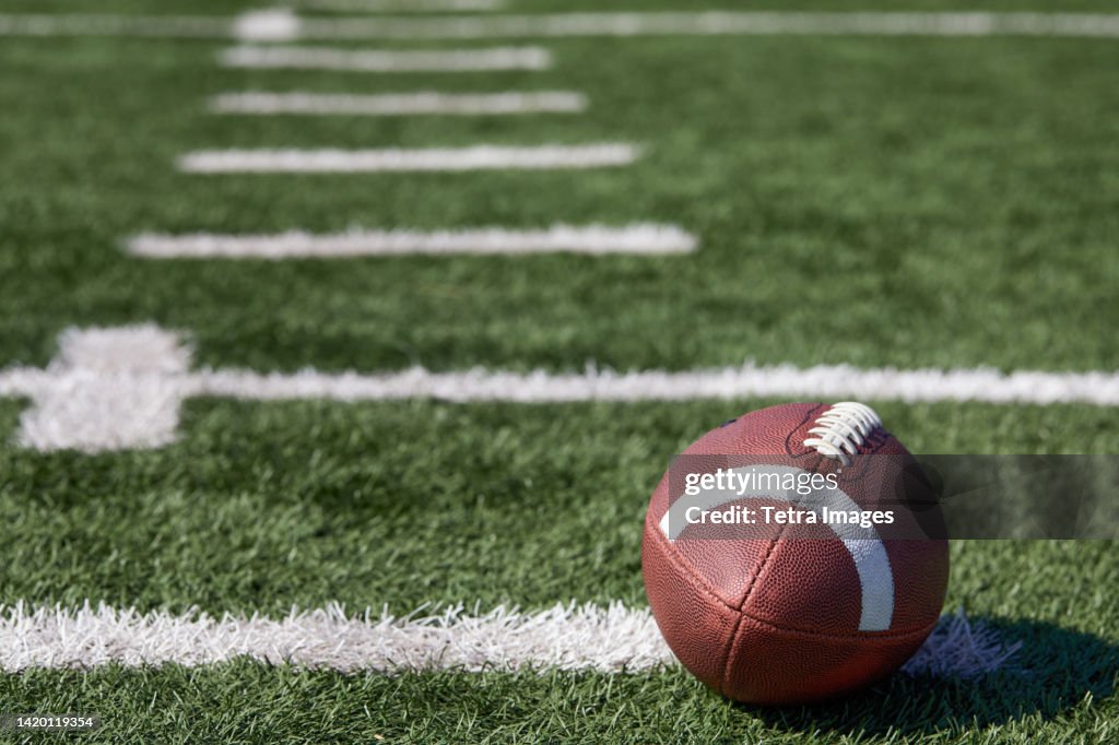 American football ball at yard line markers on playing field