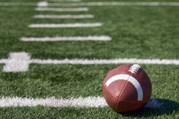 american football ball at yard line markers on playing field - american football stock pictures, royalty-free photos & images
