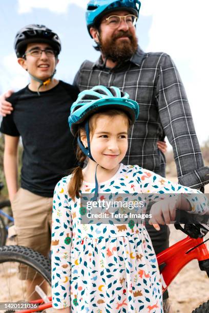 father with children (8-9, 14-15) wearing bike helmets - teenager cycling helmet stock pictures, royalty-free photos & images