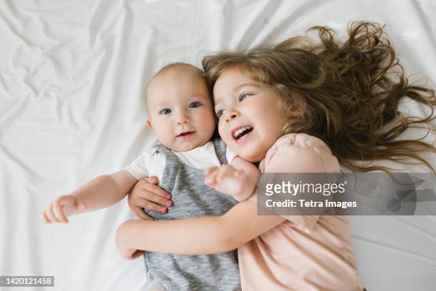 girl (2-3) hugging baby brother (6-11 months) - baby 3 months stock-fotos und bilder