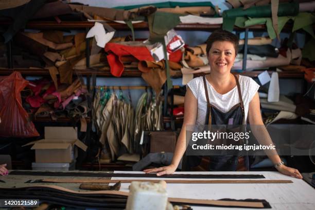 femme souriante dans un atelier de cuir - maroquinerie photos et images de collection