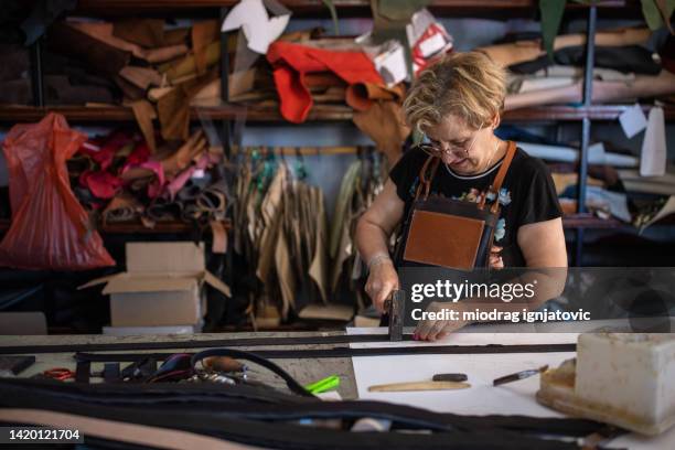 senior woman working in a leather workshop - leather craft stock pictures, royalty-free photos & images