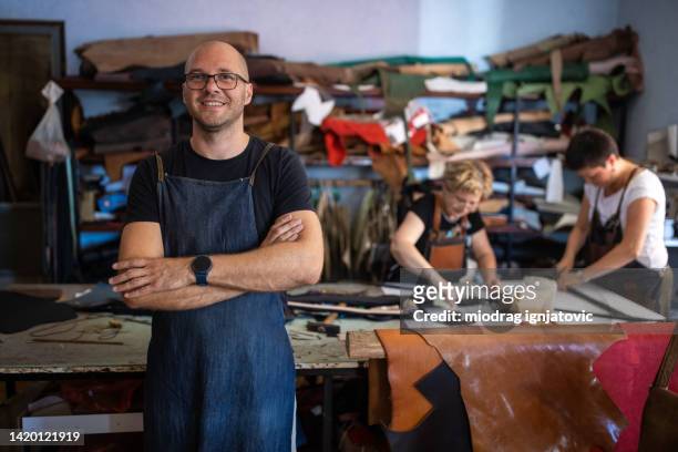 adult man smiling in a leather workshop - leather craft stock pictures, royalty-free photos & images