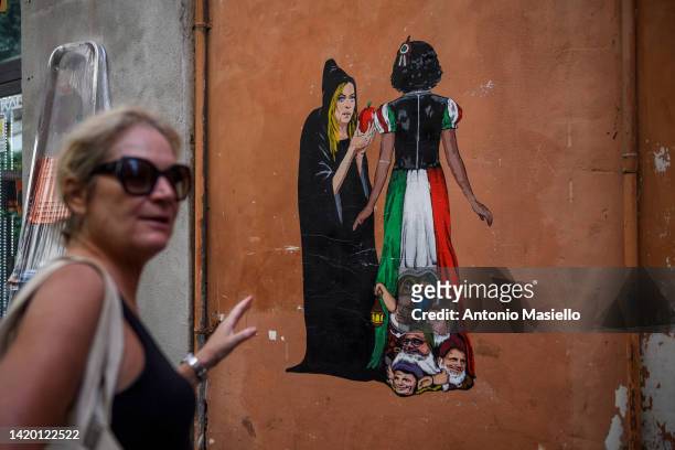 People walk by the mural painted by the street artist Harry Greb depicting the leader of "Fratelli d'Italia" political party Giorgia Meloni seducing...