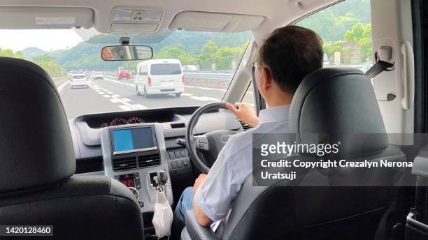 rear view / back view of a man driving thru expressway  seen from the passengers point of view.  taken on smartphone - drivers seat stock pictures, royalty-free photos & images