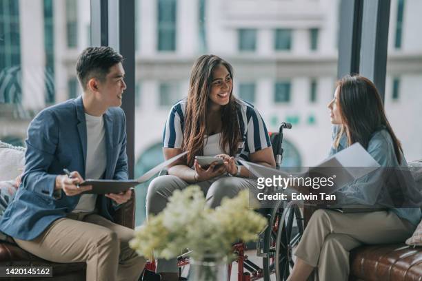 indian female white collar worker in wheelchair discussion in office lounge with colleague - accessibility stock pictures, royalty-free photos & images