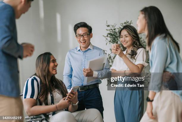 indian white collar female worker in wheelchair having cheerful discussion leading conversation with colleague in creative office workstation beside window - pessoa de cor imagens e fotografias de stock