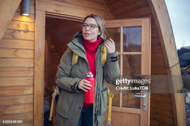 the female tourist enjoys the view in front of the wooden house where she is staying. isl - shack stockfoto's en -beelden