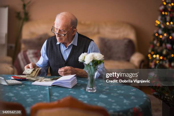 worried elderly man taking care of his finances during new year eve - christmas budget stock pictures, royalty-free photos & images