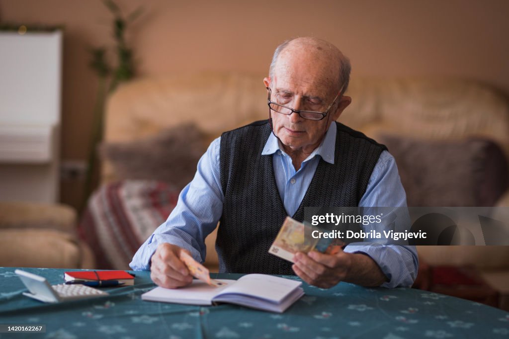 Senior man wearing reading glasses when counting pension money