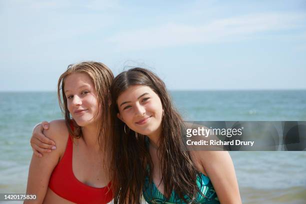 portrait of two teenage girls hugging at the beach - junge 13 jahre oberkörper strand stock-fotos und bilder
