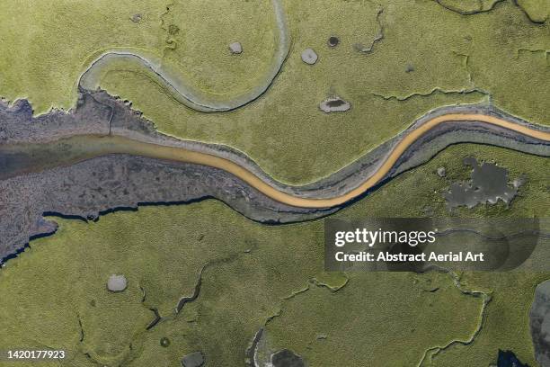 river channel flowing across a marshland seen from a drone point of view, iceland - nun river estuary stock-fotos und bilder