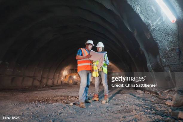 construction workers looking at blueprint in tunnel - mining helmet stock pictures, royalty-free photos & images