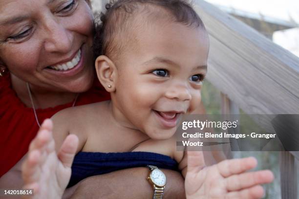 smiling grandmother holding granddaughter outdoors - jamaikanischer abstammung stock-fotos und bilder