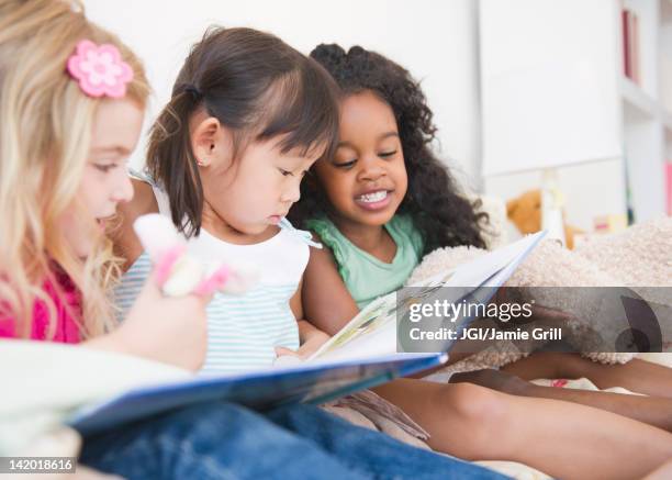 girls reading book together - nursery school child stock pictures, royalty-free photos & images