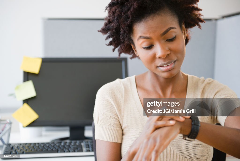 Black businesswoman checking the time at desk