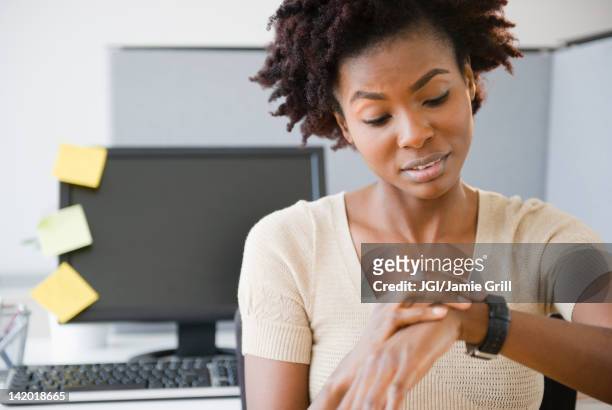 black businesswoman checking the time at desk - cross bores stock pictures, royalty-free photos & images