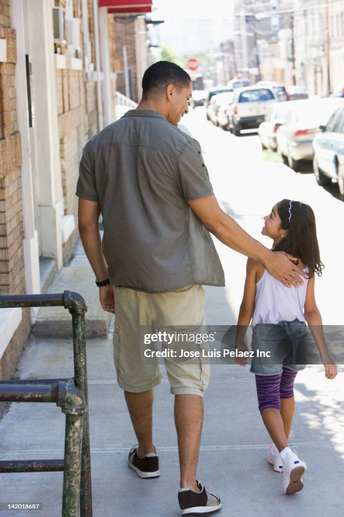 Father and daughter walking on sidewalk