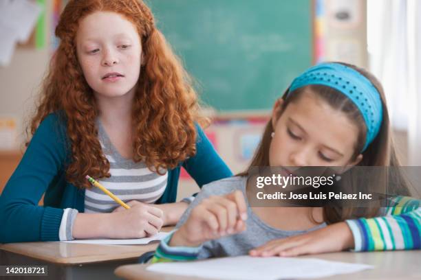 girl trying to copy off of student's paper in classroom - writing copy stock pictures, royalty-free photos & images