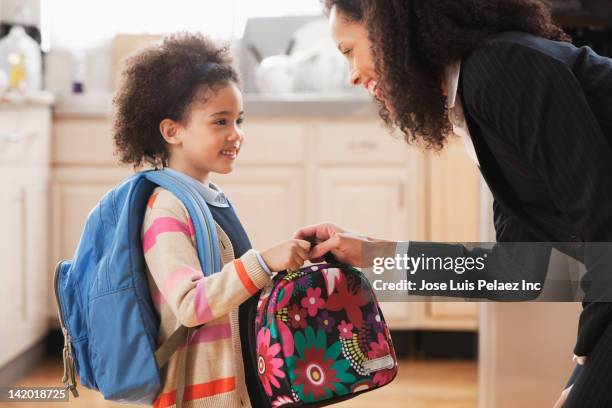 mixed race mother handing lunch box to daughter - kids backpack stock pictures, royalty-free photos & images