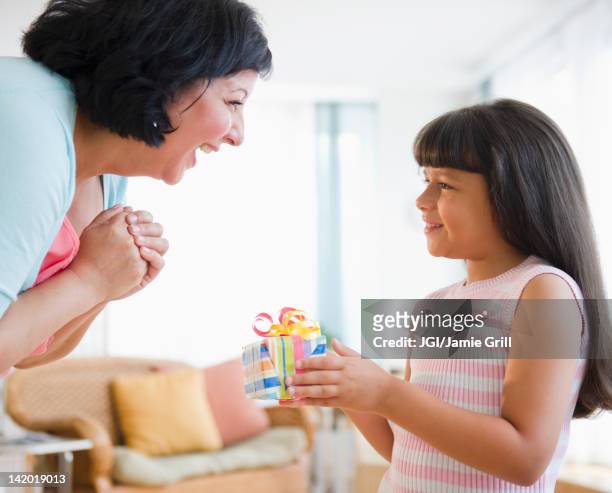 hispanic girl giving her mother birthday gift - hand over mouth stock pictures, royalty-free photos & images