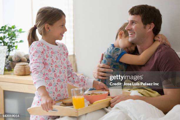 caucasian children bringing father breakfast in bed - three people bed stock pictures, royalty-free photos & images