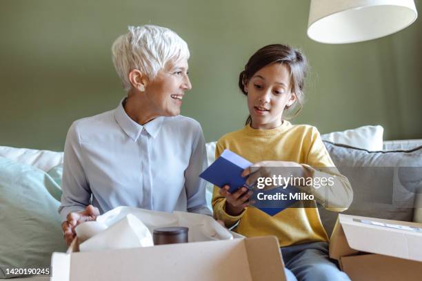 grandmother and granddaughter opening cardboard box with online purchase order - elderly receiving paperwork stock pictures, royalty-free photos & images