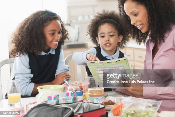 mixed race mother going over homework with daughters - workbook stock pictures, royalty-free photos & images