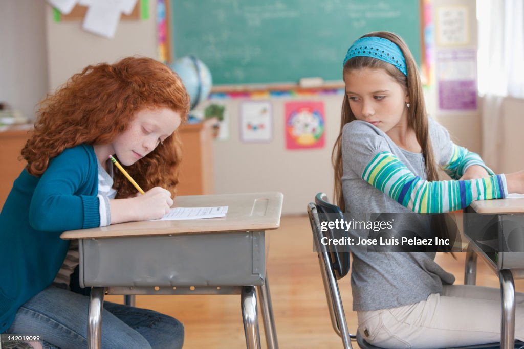 Girl trying to copy off of student's paper in classroom