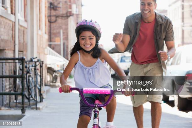 father teaching daughter to ride bicycle - bicycle daughter stock-fotos und bilder