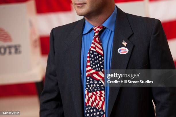 mixed race businessman standing in polling place - lapel stock-fotos und bilder