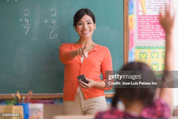 teaching calling on student in classroom - two female teachers blackboard stockfoto's en -beelden